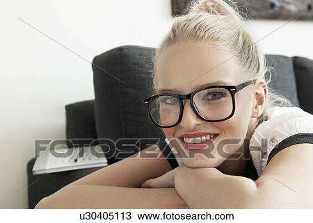 Stock Image - Teenage girl smiling on sofa. Fotosearch