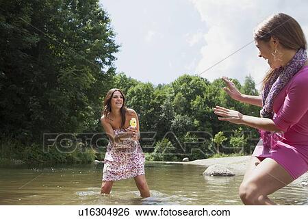 Stock Photograph - Teenage girls playing in rural stream. Fotosearch