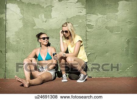 Stock Photo - Teenage girls sharing headphones. Fotosearch