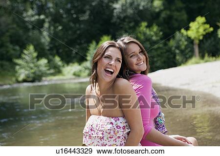 Stock Photo - Teenage girls sitting in rural stream. Fotosearch