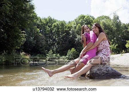 Teenage girls sitting on rock in stream View Large Photo Image Stock Image - Teenage girls sitting on rock in stream. Fotosearch