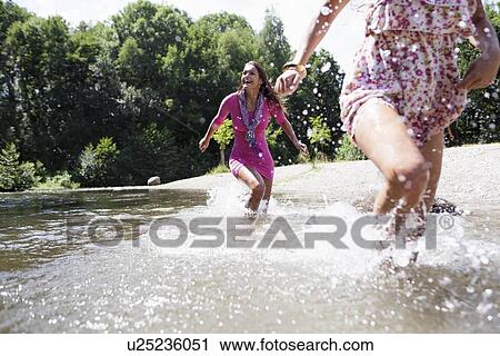 Stock Image - Teenage girls splashing in rural stream. Fotosearch