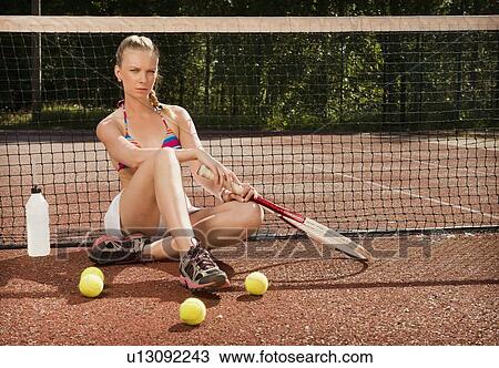 Stock Image - Tennis player sitting on court. Fotosearch