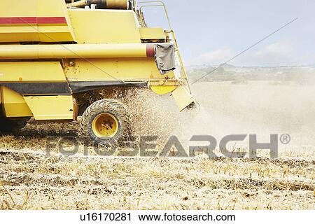Stock Image - Thresher working in crop field. Fotosearch