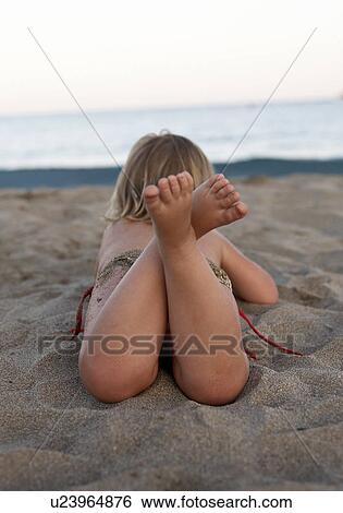Stock Photograph - Toddler laying on beach. Fotosearch