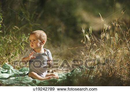Toddler sitting on blanket in field View Large Photo Image Stock Photo - Toddler sitting on blanket in field. Fotosearch