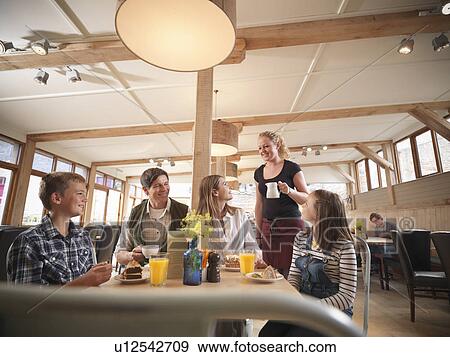 Stock Photo - Waitress serving family in restaurant. Fotosearch