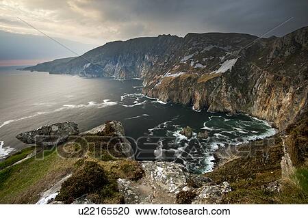 Stock Image - Waves crashing on rocky cliffs. Fotosearch