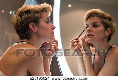 Picture - Woman applying makeup in mirror. Fotosearch