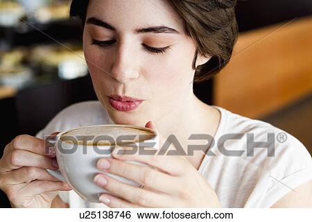 Stock Photograph - Woman blowing on coffee in cafe. Fotosearch