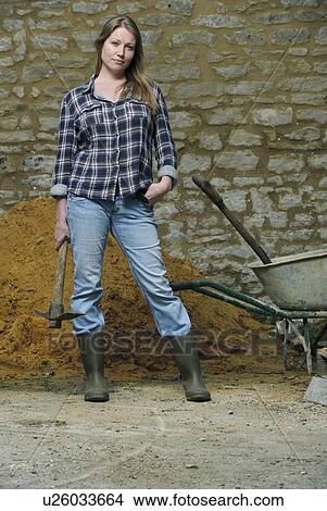 Picture - Woman carrying pickaxe in yard. Fotosearch