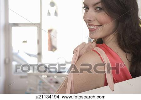 Picture - Woman carrying shopping bag in store. Fotosearch