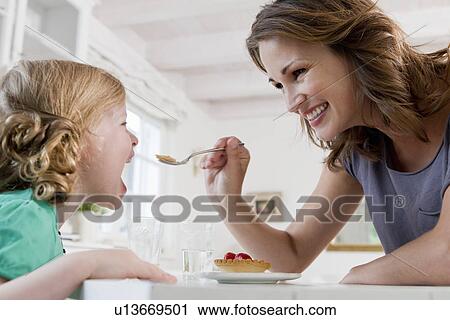 Woman feeding daughter breakfast View Large Photo Image Stock Image - Woman feeding daughter breakfast. Fotosearch