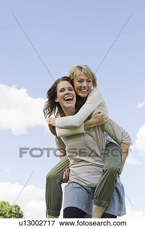 Stock Photo - Woman giving her friend a piggy back. Fotosearch