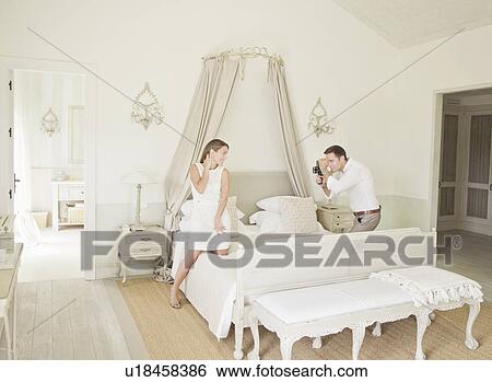 Stock Photograph - Woman having picture taken in bedroom. Fotosearch