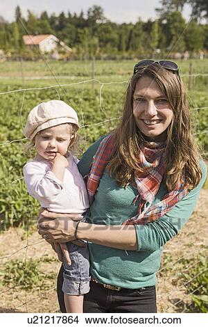 Picture - Woman holding daughter in berry patch. Fotosearch
