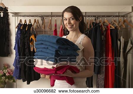 Woman holding folded clothes in store View Large Photo Image Stock Image - Woman holding folded clothes in store. Fotosearch