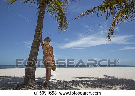 Stock Photo - Woman holding tropical fruit on beach. Fotosearch