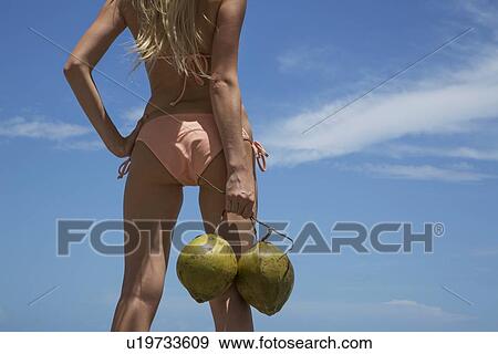 Stock Photo - Woman in bikini holding tropical fruit. Fotosearch