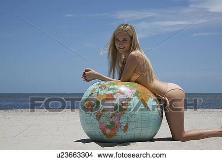 Picture - Woman in bikini leaning on globe. Fotosearch