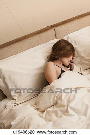 Stock Image - Woman laying in bed. Fotosearch