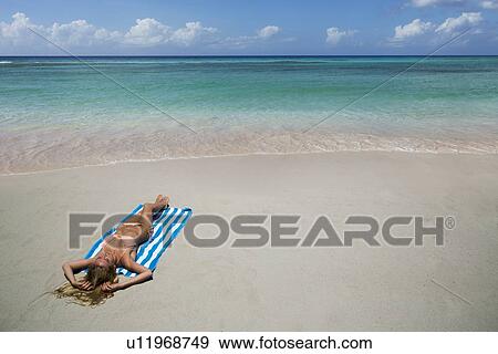 Woman laying on towel on beach View Large Photo Image Stock Photo - Woman laying on towel on beach. Fotosearch