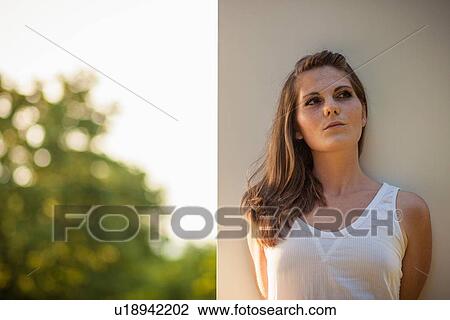 Stock Image - Woman leaning against wall outdoors. Fotosearch