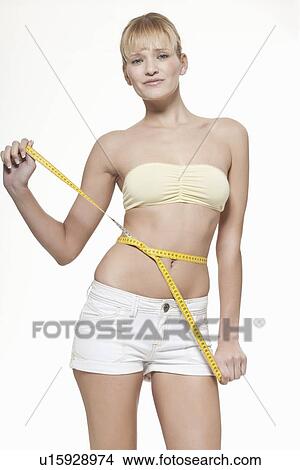 Picture - Woman measuring her waistline. Fotosearch