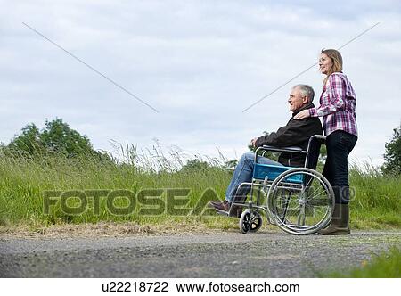 Woman pushing father in wheelchair View Large Photo Image Stock Image - Woman pushing father in wheelchair. Fotosearch