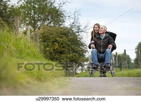 Woman pushing father in wheelchair View Large Photo Image Stock Image - Woman pushing father in wheelchair. Fotosearch