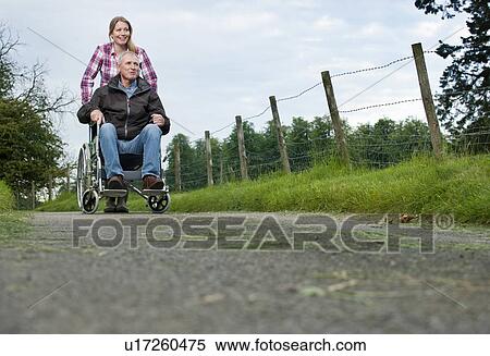 Stock Photography - Woman pushing father in wheelchair. Fotosearch