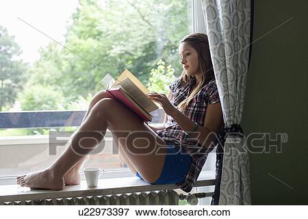 Stock Photo - Woman reading book in windowsill. Fotosearch