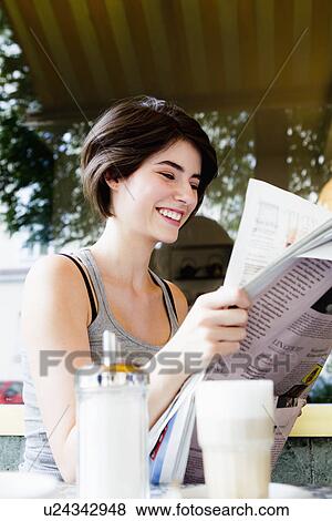Stock Photo - Woman reading newspaper in cafe. Fotosearch