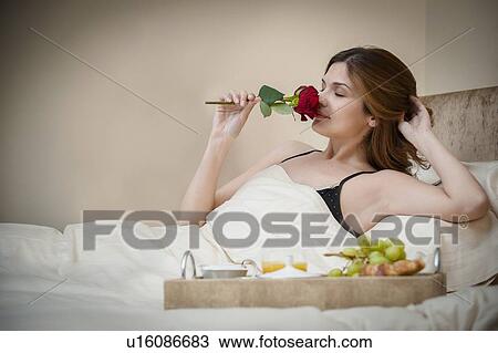Stock Image - Woman relaxing with breakfast in bed. Fotosearch