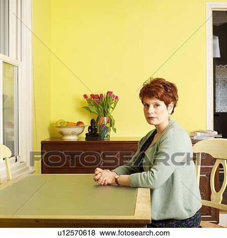 Woman sitting at kitchen table View Large Photo Image Stock Photo - Woman sitting at kitchen table. Fotosearch