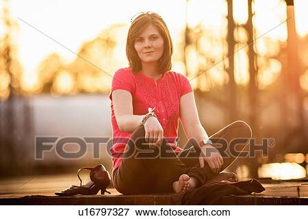 Stock Photo - Woman sitting cross-legged on stone wall. Fotosearch