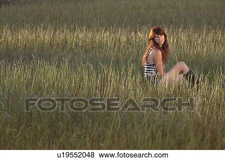 Woman sitting in grassy field View Large Photo Image Stock Photo - Woman sitting in grassy field. Fotosearch