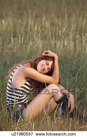 Woman sitting in grassy field View Large Photo Image Stock Photo - Woman sitting in grassy field. Fotosearch