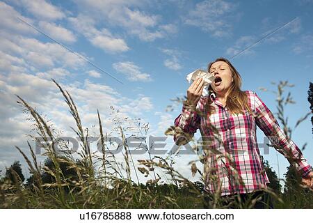 Stock Photo - Woman sneezing in tall grass. Fotosearch