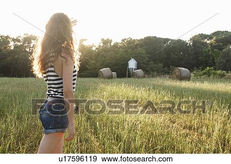 Stock Photo - Woman standing in grassy field. Fotosearch
