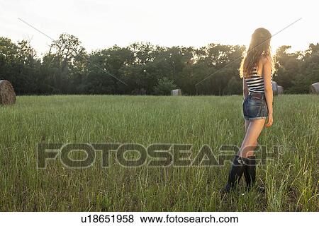 Stock Photo - Woman standing in grassy field. Fotosearch