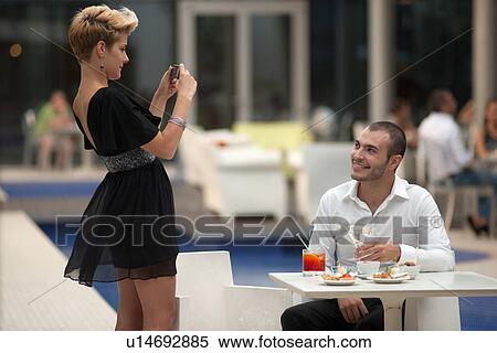 Stock Photography - Woman taking picture of boyfriend. Fotosearch