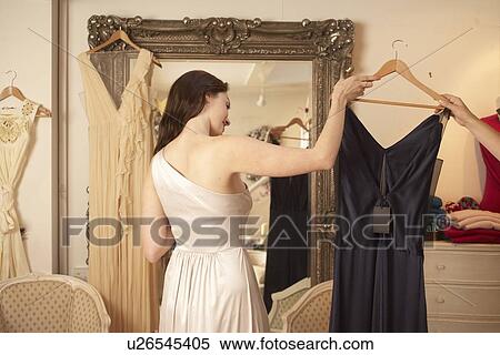 Stock Photography - Woman trying on dress in store. Fotosearch