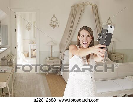 Stock Photo - Woman using video camera in bedroom. Fotosearch