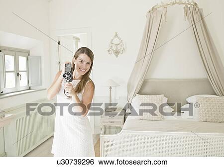 Stock Photograph - Woman using video camera in bedroom. Fotosearch
