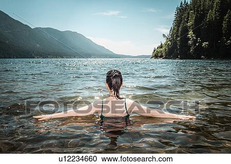 Stock Image - Woman walking in still lake. Fotosearch
