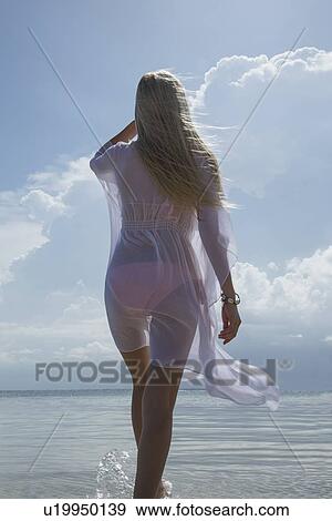 Stock Photo - Woman walking in still ocean water. Fotosearch