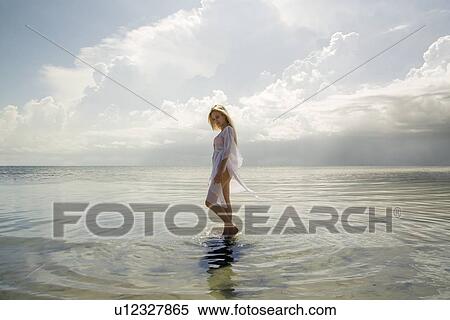 Stock Photography - Woman walking in still ocean water. Fotosearch