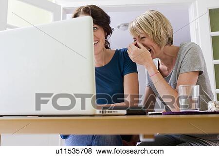 Stock Photo - Women using laptop together. Fotosearch