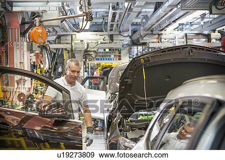 Worker fitting doors in car in car factory View Large Photo Image Stock Photo - Worker fitting doors in car in car factory. Fotosearch